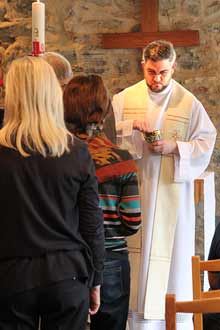 Mit Gründlichkeit geht der Priester ans Werk, er nimmt die Hostie, bricht sie und verteilt den „Leib Christi“ unter den Gläubigen (Foto: Karl Grünberg) 